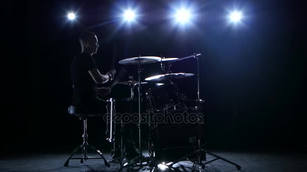 O baterista toca a melodia na bateria energeticamente. Fundo preto. Luz traseira. Silhueta — Vídeo de Stock