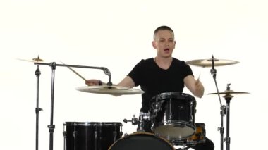 Davulcu bir davul setinde güçlü müzik çalar. Beyaz arka plan