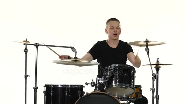 Барабанщик грає енергійною музикою на барабанної установки. Білий фон — стокове відео