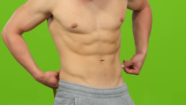 Мужчина без рубашки измеряет объем талии. Зеленый экран — стоковое видео
