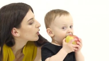 Bebek bir elma yiyor, beğendi. Beyaz arka plan. Ağır çekim