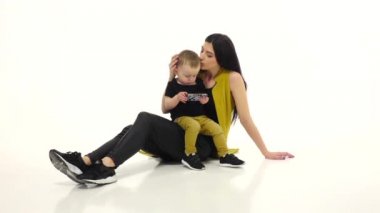 Kız söyler ve bir şey çocuğunu smartphone üzerinde gösterir. Beyaz arka plan. Ağır çekim