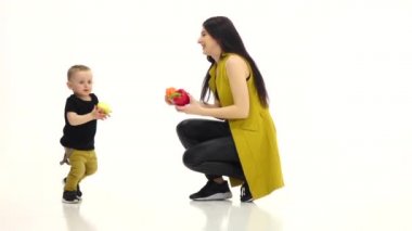 Anne iki biber tutar, bebek bir elma var ve o kaçtı. Beyaz arka plan. Ağır çekim