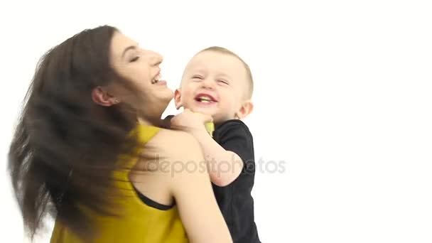 Малыш смеется, держит в руках яблоко, и его мать поворачивается. Белый фон. Медленное движение — стоковое видео