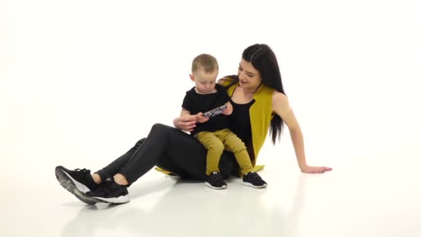 Vrouw zit op de grond met haar baby, ze is aaien zijn haar. Witte achtergrond. Slow motion — Stockvideo