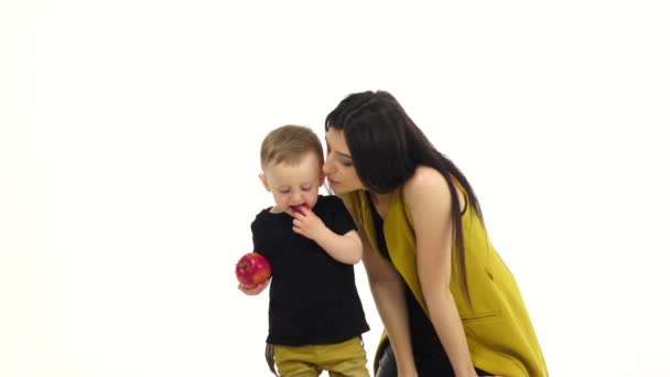Παιδί με ένα μήλο στα χέρια του, τρέχει μακριά από τη μητέρα του. Λευκό φόντο. Αργή κίνηση — Αρχείο Βίντεο