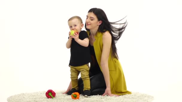 Moeder kussen haar baby, lacht hij. Witte achtergrond. Slow motion — Stockvideo