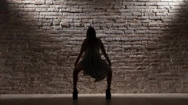 Yüksek topuklu kadın dans bir tuğla duvara twerk. Siluet