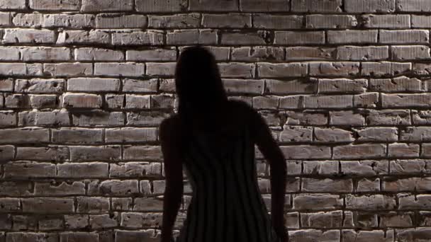 Ενεργητική γυναίκα σε ψηλά τακούνια χορού twerk ενάντια σε έναν τοίχο από τούβλα. Σιλουέτα. Κοντινό πλάνο — Αρχείο Βίντεο