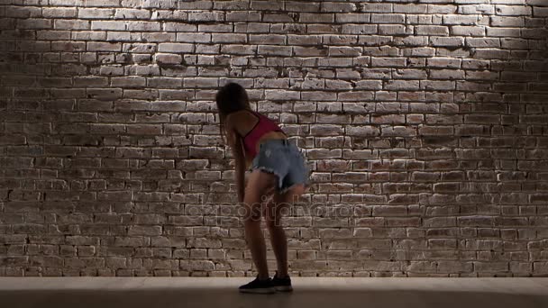 Woman sexy in crop top and denim shorts dance twerk against a brick wall — Stock Video