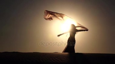 Kız sahilde oryantal dans onun elinde bir örtü ile. Siluet. Ağır çekim