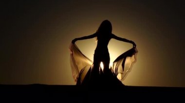 Kız sahilde oryantal dans onun elinde bir örtü ile. Siluet. Ağır çekim