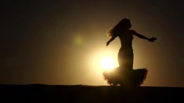 Sıcak bir gün batımı çerçevede incelikle kız dansçı dansları. Siluet. Ağır çekim