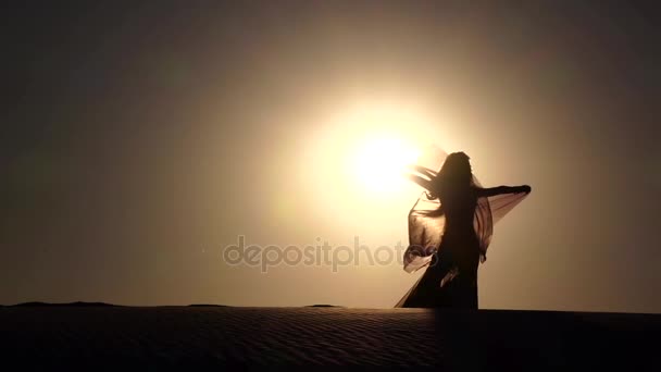 Ballerina con un velo tra le mani che balla danza del ventre sulla spiaggia. Silhouette. Rallentatore — Video Stock