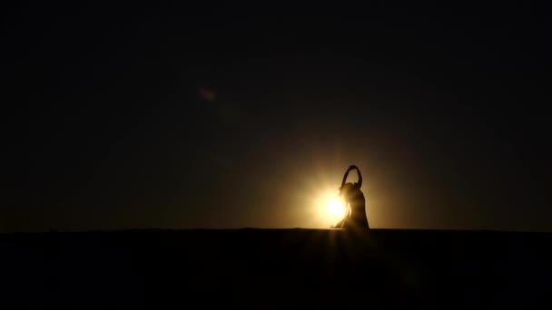 Chica realiza hermosa danza del vientre en el fondo de la puesta del sol. Silueta. Movimiento lento — Vídeos de Stock