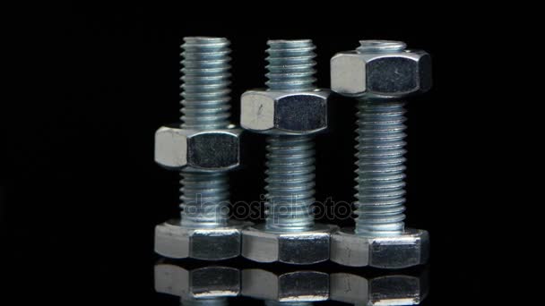 Tre bulloni metallici con dadi avvitati ruotano su fondo nero — Video Stock