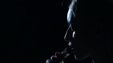 Kız elektronik sigara içiyor. Siyah arka plan. Yakın çekim. Siluet. Ağır çekim