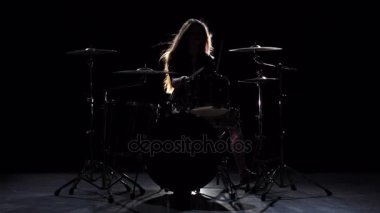Enerjik müzik davul, oynamaya başladı kızdır. Siyah arka plan. Siluet. Ağır çekim