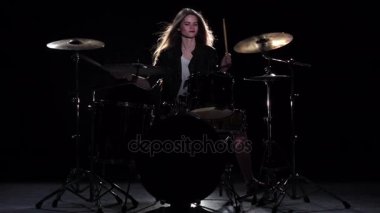 Baterist kız enerjik müzik, o gülümsüyor çalmaya başlar. Siyah arka plan. Ağır çekim
