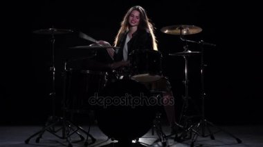 Baterist kız enerjik müzik, o gülümsüyor çalmaya başlar. Siyah arka plan. Ağır çekim