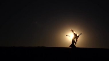 Gün batımını kız zarif hareketleri yapar. Ağır çekim. Siluet