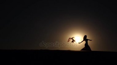 Sahilde oryantal dans onun elinde bir örtü ile dansçı. Siluet. Ağır çekim