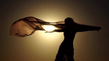 Deniz kıyısı gurl gün batımına karşı vücudu incelikle dans ediyor. Siluet. Ağır çekim