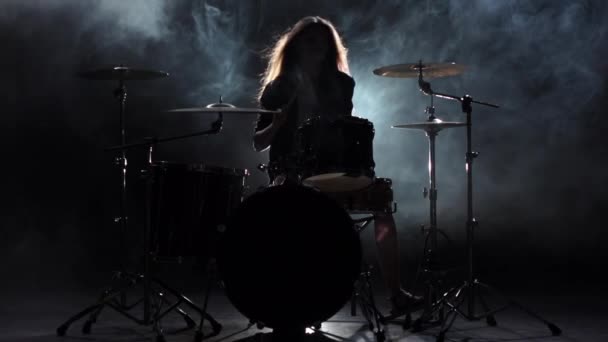 Meisje is kicks van het bespelen van drums, energieke muziek spelen. Zwarte rook achtergrond. Silhouet. Slow motion — Stockvideo