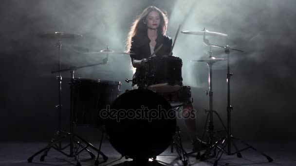 Дівчина грає на барабані, який вона любить товкти на млинцях. Чорний дим фону. Повільний рух — стокове відео