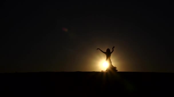 Brunette veil in her hands dancing belly dance on the beach. Silhouette. Slow motion — Stock Video