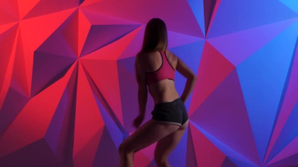 Mädchen tanzt energiegeladene Tanzbeute in kurzen Hosen auf hellem grafischen Hintergrund — Stockvideo
