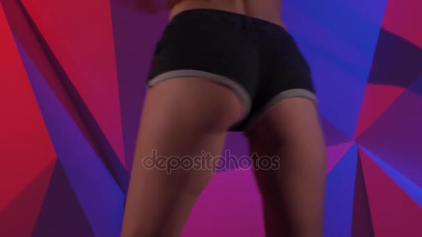 Mulher energética dançando bunda em shorts em fundo gráfico brilhante. Fechar — Vídeo de Stock