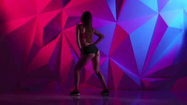 Holka tančí energický tanec kořist v šortkách na světlé grafické pozadí. Zpomalený pohyb — Stock video