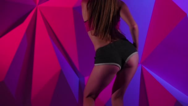 Танец секса с девушкой в шортах на ярком графическом фоне. Медленное движение. Закрыть — стоковое видео