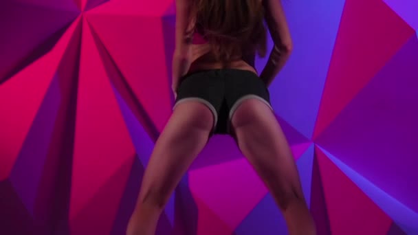 Twerk 在运动短裤跳舞上明亮的图形背景的女人。慢动作。关闭 — 图库视频影像