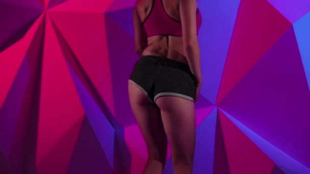 Danseres meisje sexy dans buit in korte broek op heldere grafische achtergrond. Slow-motion. Close-up — Stockvideo
