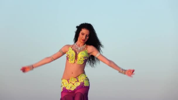 Грациозный танцор против неба танцует танец живота в блестящем наряде — стоковое видео
