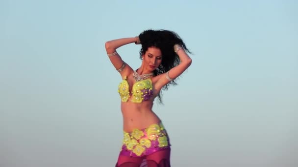 Професійна танцівниця в блискучому костюмі робить сексуальні рухи проти блакитного неба — стокове відео