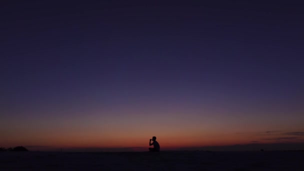 Guy rookt een elektronische sigaret tegen de zonsondergang met zijn ontspannen. Silhouet — Stockvideo