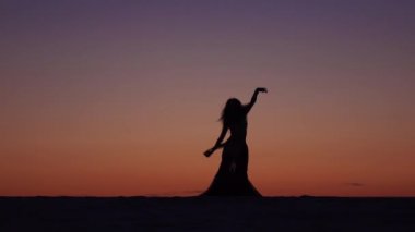 Dansçı bir peçe onun elinde tutan, sahilde bir oryantal dans. Siluet