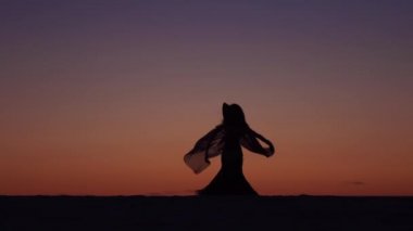 Deniz kıyısı gurl gün batımına karşı vücudu incelikle dans ediyor. Siluet