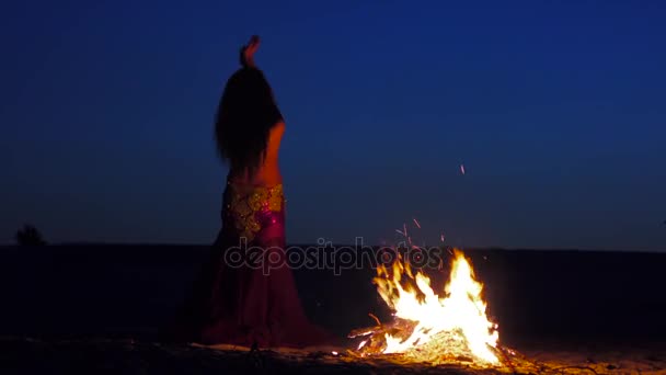 Late night a girl in the sand dancing belly dancing near a bright campfire — Stock Video