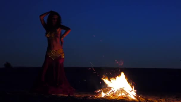 Brunetka tančí břišní tance k ohni, proti krásný západ slunce — Stock video