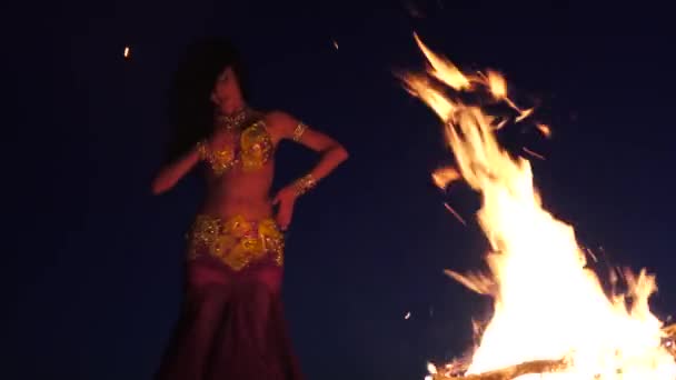 Spätabends tanzt ein Mädchen im Sand Bauchtanz am hellen Lagerfeuer — Stockvideo