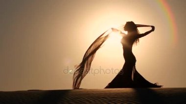 Kız sahilde oryantal dans onun elinde bir örtü ile. Siluet