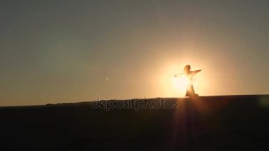 Kız çok güzel bir göbek dansı karşı günbatımı, zarif hareketleri yapar. Siluet