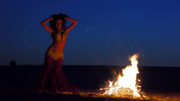 Tanečnice kroutí břišní tanec, že vypadá sexy, kolem ohně — Stock video