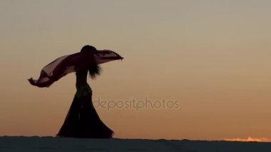 Dansçı bir peçe onun elinde tutan, sahilde bir oryantal dans. Siluet