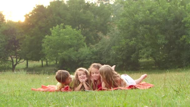 Les petits enfants lisent le livre et grimace dans le jardin. Mouvement lent — Video