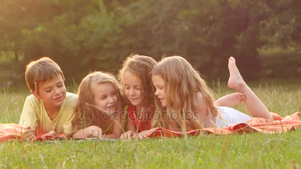 Boy and girls read a book in the garden lying on the blanket beautiful summer day. Close up — Stock Video